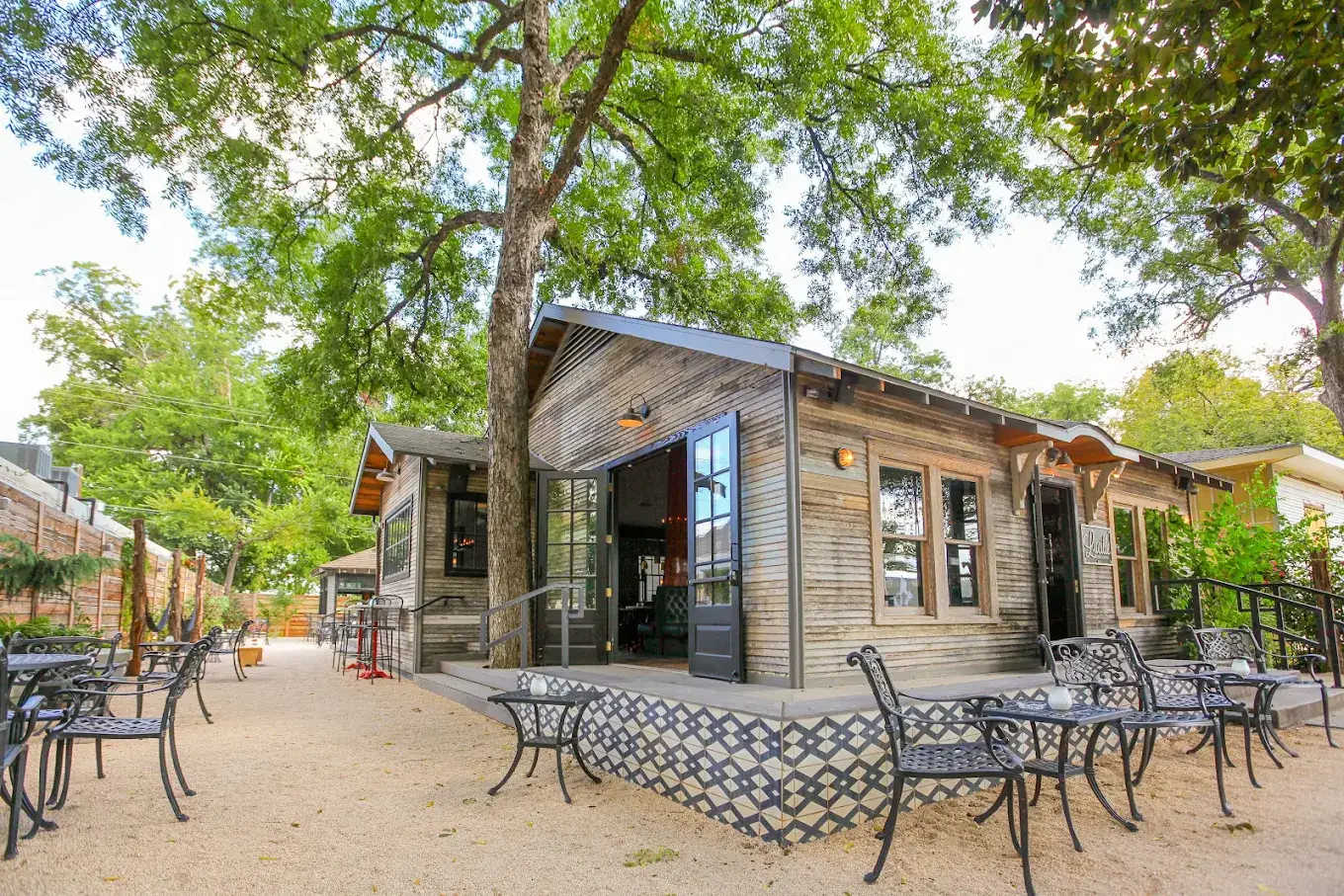 The renovated wooden house at 77 Rainey St with its tiled porch and wrought-iron patio chairs
