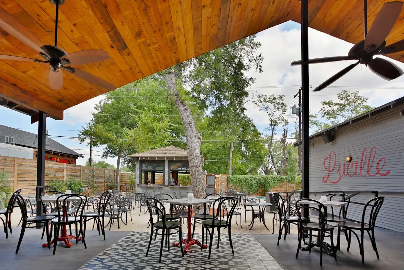 Covered patio with café tables and red pedestal bases looking out to the yard